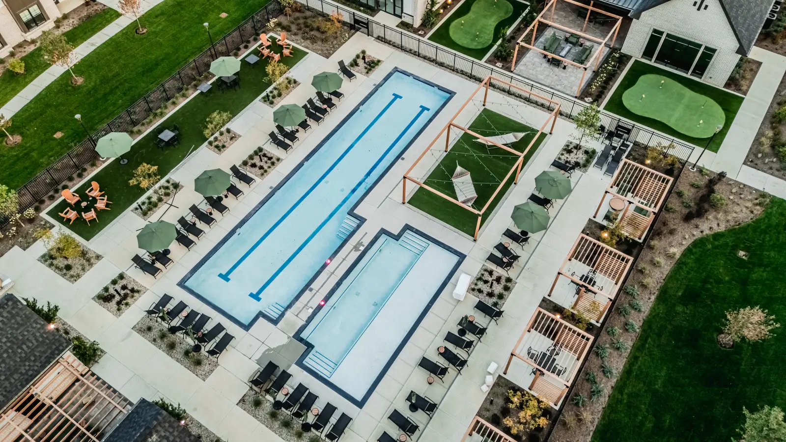 Elevated aerial view of a resort-style pool deck with lap lanes, shaded hammock area, lounge seating, and outdoor social spaces.