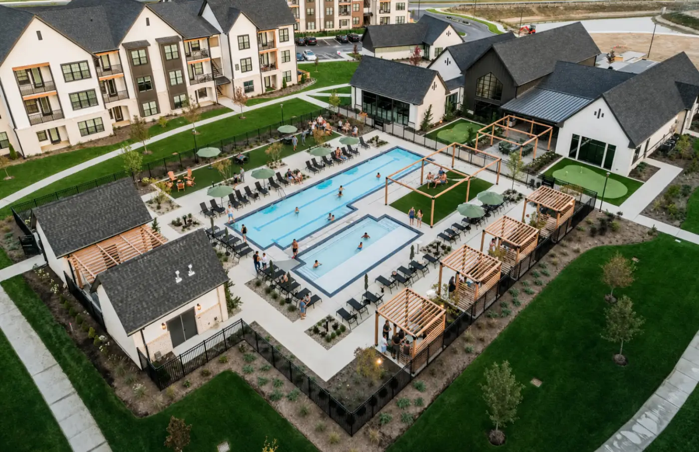Aerial view of resort-style pool and clubhouse amenities with residents gathering outdoors