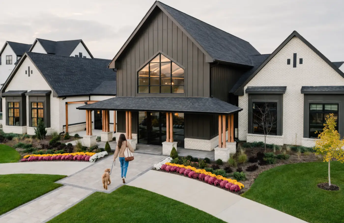 Resident walking a dog toward the clubhouse entrance and landscaped grounds