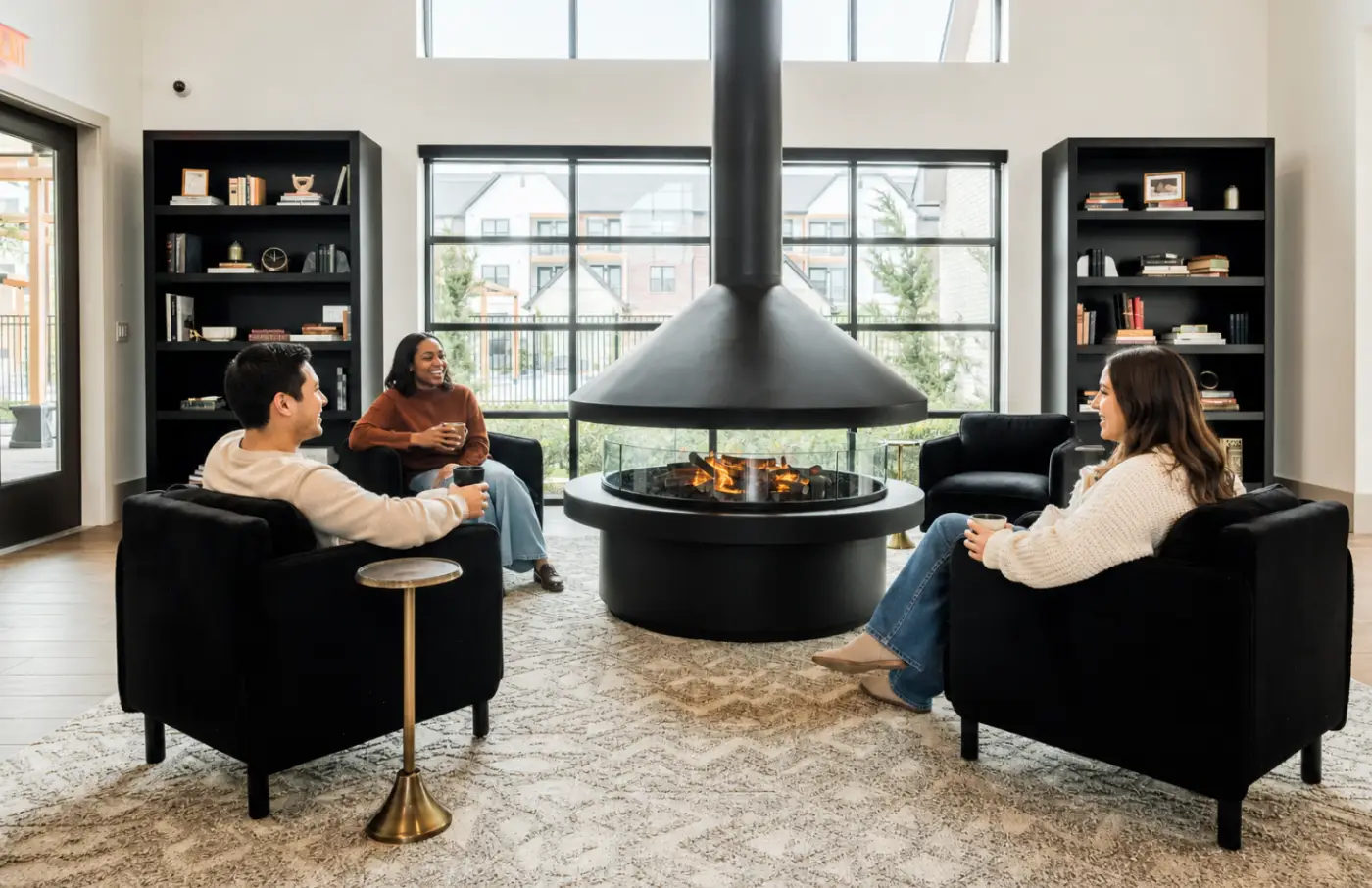 Residents gather around a modern fireplace in the clubhouse lounge