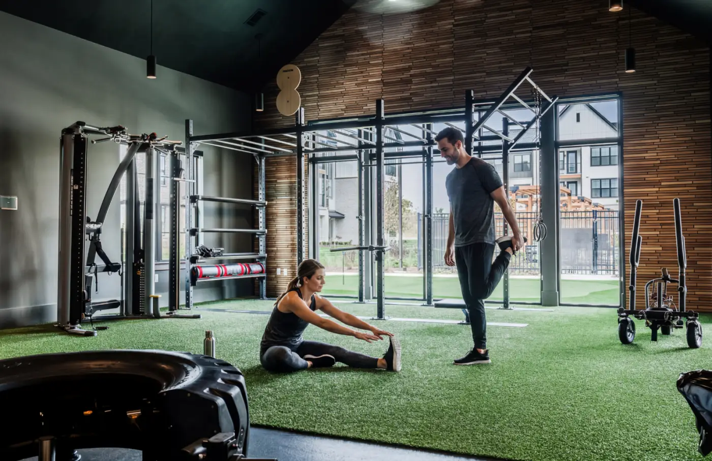 Residents stretching in a fitness studio with turf training area and strength equipment
